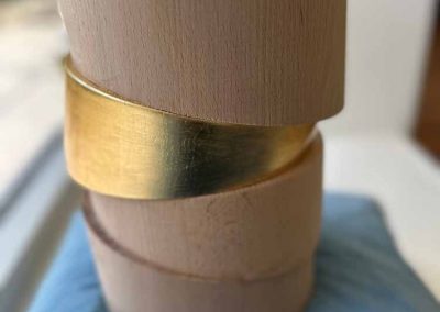 Geschwungene Urne aus Holz mit einem Goldring