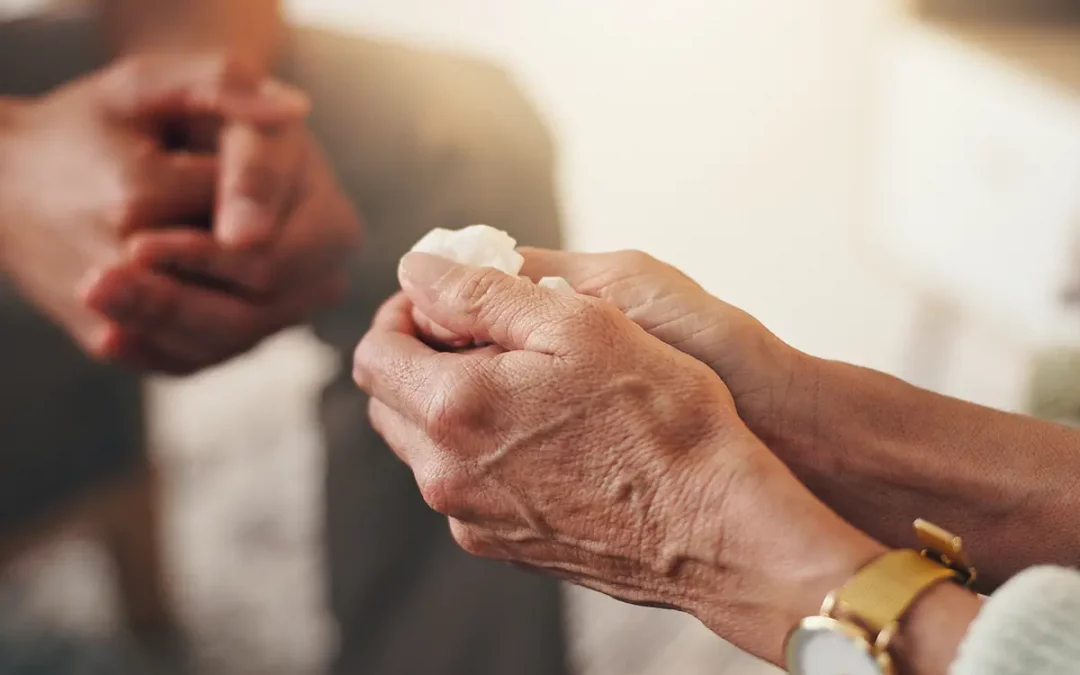 Trauernde Person hält Taschentuch in der Hand in Gesellschaft einer tröstenden Person